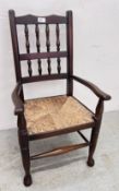 A CHILD'S TRADITIONAL ELBOW CHAIR WITH WOVEN RUSH SEAT.