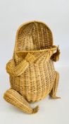 A WICKER WASTE PAPER BIN FASHIONED AS A FROG WITH GLASS MARBLE EYES.