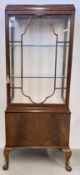 A C20TH WALNUT DISPLAY CABINET WITH SINGLE DOOR WITH OVOLU ASTRAGALS AND PLAIN DOOR BELOW,