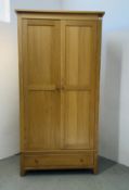 A MODERN CORNDELL OAK TWO DOOR WARDROBE ON SINGLE DRAWER TO BASE.