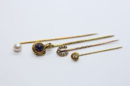 A GROUP OF FOUR VINTAGE YELLOW METAL STICK PINS TO INCLUDE HORSE SHOE, PEARL AND SNAKE EXAMPLE.