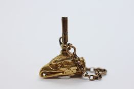 AN ANTIQUE YELLOW METAL POCKET WATCH KEY FOB DESIGNED IN THE FORM OF AN EAGLES HEAD INSET WITH A