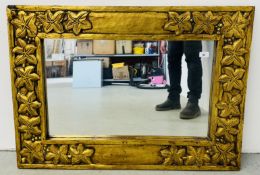 A GILT FRAMED WALL MIRROR BEARING CARVED LEAF DECORATION, 100 X 71CM.