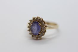 14CT YELLOW GOLD DRESS RING, THE CENTRAL OVAL BLUE STONE SURMOUNTED BY 16 SMALL DIAMONDS.