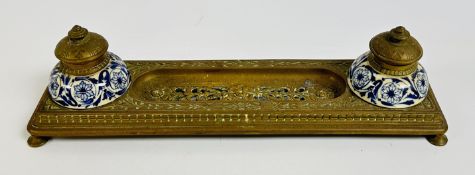 AN ANTIQUE BRASS INKWELL DESK SET WITH INTRICATE CUT OUT DESIGNS AND ORIGINAL BLUE AND WHITE
