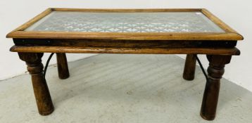 AN EASTERN HARD WOOD OCCASIONAL TABLE WITH METAL CRAFT DETAIL AND CLEAR GLASS INSERT,
