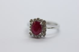 14CT WHITE GOLD DRESS RING, THE CENTRAL OVAL RED STONE SURROUNDED BY 16 SMALL DIAMONDS.