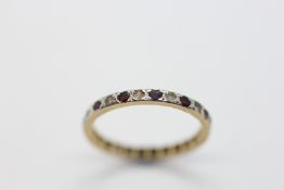 AN UNMARKED ETERNITY RING SET WITH RED AND WHITE STONES (SOME LOSSES, CONSIDERABLE WEAR).