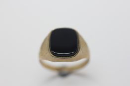 A 9CT GOLD GENTLEMAN'S SIGNET RING SET WITH BLACK STONE.