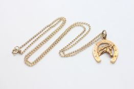 A 9CT YELLOW GOLD HORSESHOE DESIGN PENDANT STRUNG FROM AN UNMARKED YELLOW METAL FINE LINK CHAIN,