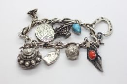 A VINTAGE SILVER AND WHITE METAL CHARM BRACELET TO INCLUDE A LUCKY HORSESHOE,