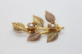 A TWO TONE GOLD LEAF BROOCH MARKED 10K SET WITH TWO SEED PEARLS.