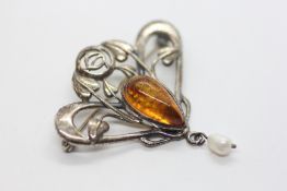 A SILVER NOUVEAU STYLE BROOCH SET WITH AN AMBER TYPE PANEL AND A PEARL DROP.