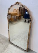 A REPRODUCTION ORNATE ARCHED WALL MIRROR WITH DECORATIVE GILT FRAME.