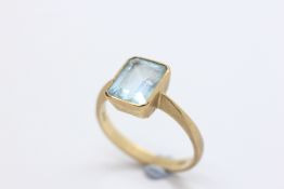 A 9CT YELLOW GOLD AQUAMARINE SOLITAIRE RING, THE RECTANGULAR STONE IN A RUB OVER SETTING.