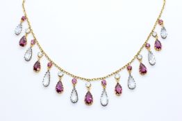 AN UNMARKED YELLOW METAL NECKLACE SUPPORTING PEAR SHAPED CLAW SET AMETHYSTS AND WHITE STONES OF
