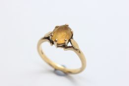 A 9CT YELLOW GOLD RING, THE OVAL YELLOW STONE CLAW SET,