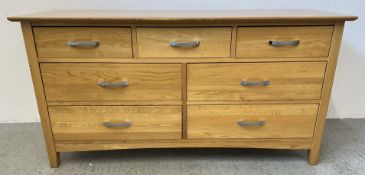 A MODERN OAK 3 OVER 4 DRAWER SIDEBOARD, W 146CM, D 43CM, H 76CM WITH A MATCHING WALL MIRROR.
