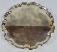 A SOLID SILVER SCOLLOP EDGED SALVER STANDING ON FOUR SCROLLED FEET, DIAMETER 41CM,