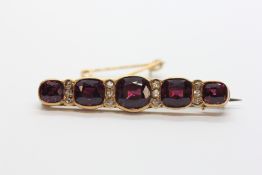 AN UNMARKED YELLOW METAL BAR BROOCH, ASSUMED GOLD, SET WITH FIVE GRADUATED AMETHYSTS,