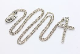 AN UNMARKED WHITE METAL DIAMOND SET CROSS PENDANT STRUNG FROM A FINE WHITE METAL NECKLACE,