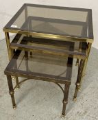 A NEST OF BRASS FRAMED TABLES WITH SMOKED GLASS TOPS.