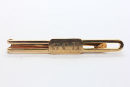 A 14CT YELLOW GOLD TIE SLIDE MARKED 10K, THE PANEL ENGRAVED WITH THE INITIALS G.C.B.