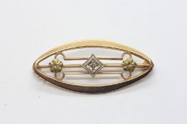 A DECO GOLD BROOCH MARKED 10K OF NAVETTE FORM THE CENTRE SET WITH SMALL BRILLIANT CUT DIAMOND.