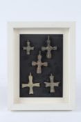 A FRAMED GROUP OF FIVE SMALL BRONZE CROSSES. Frame 22.5cms x 17.5cms.