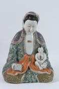 A CHINESE PORCELAIN STATUE OF GUANYIN holding a baby and a calligraphy tablet, with famille rose