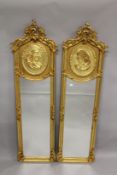 A PAIR OF NARROW GILTWOOD MIRRORS, with moulded gilded portrait panels. 5ft 9ins high x 1fy 8ins