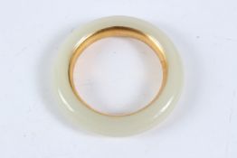 A WHITE JADE GOLD LINED BANGLE.