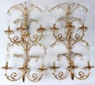 A SET OF FOUR ORMOLU THREE BRANCH WALL APPLIQUES, with cut glass drops. 36cms wide x 38cms high.