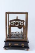 A REPRODUCTION BRASS CONGREVE ROLLING BALL CLOCK, in a glass case with mahogany stand. 40cms high
