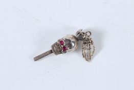 A SILVER SKULL HEAD AND HAND WATCH WINDER.