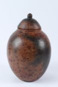 AN AFRICAN MOTTLED BROWN GLAZED EARTHENWARE JAR AND COVER. 32cms high.