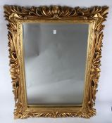 A 20TH CENTURY DECORATIVE GILT FRAMED RECTANGULAR WALL MIRROR. 3ft 10ins x 2ft 11ins.