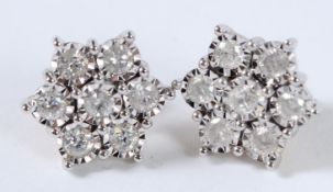 A PAIR OF 9CT GOLD 1CT SEVEN DIAMOND DAISY CLUSTER EARRINGS.
