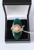 AN UNUSUAL YELLOW METAL RING, probably 18ct, set with an oval jade, mounted with diamonds and a