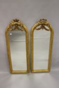 A PAIR OF NARROW GILTWOOD ARCH TOP MIRRORS, with floral swag decoration. 4ft 11ins high x 1ft