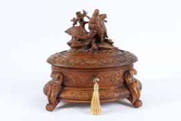 A GOOD BLACK FOREST CARVED WOOD OVAL JEWELLERY BOX with velvet interior, the top carved with two