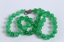 A STRING OF JADE BEADS with diamond clasp. 60cms long.