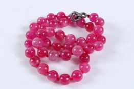 A STRING OF PINK TOURMALINE BEADS with diamond clasp. 60cms long.