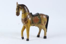 AN INDIAN CARVED WOOD AND DECORATIVELY PAINTED MODEL OF A STANDING HORSE. 24cms long.