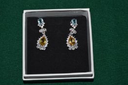 A pair of natural blue topaz and golden citrine pendant earrings.