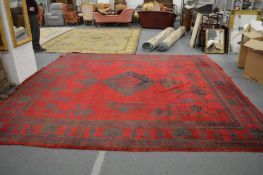 An Indian carpet, red ground with stylised decoration, some ware, 380cm x 360cm.