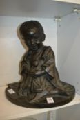 Cast bronze group of a Japanese girl seated, holding a doll in her arms.