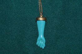 A clenched fist pendant and gilt metal chain.