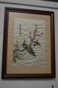 A pair of Oriental embroidered pictures depicting peacocks and other birds on a branch.