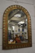 An arch shaped mirror with copper and brass frame.